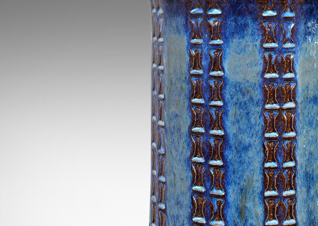 Gallery BAC cylindrical form with flared top, sprouting neck, and ornamented with columns of “I” motifs, partially glazed in a blue luster