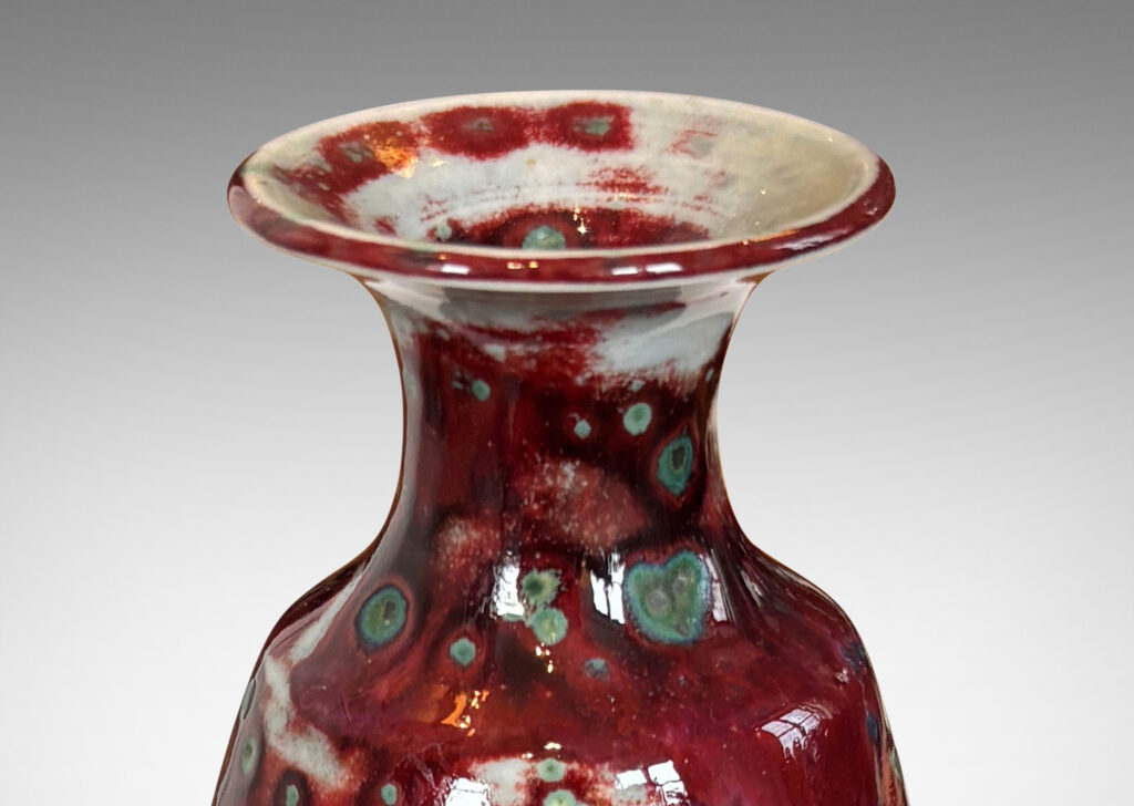 Gallery BAC tall swelling form with outstretched mouth, glazed in oxblood burgundy, with pale gray accents and green-gray dappling