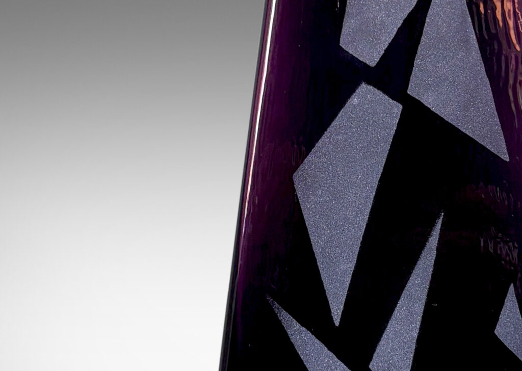 Gallery BAC tall triangular obelisk form in amethyst purple, with a polished finish ornamented with a sandblasted pattern of triangles