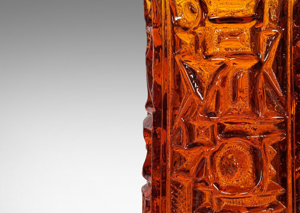 Gallery BAC round canister forms surrounded in geometric reliefs in a warm saturated whisky tone