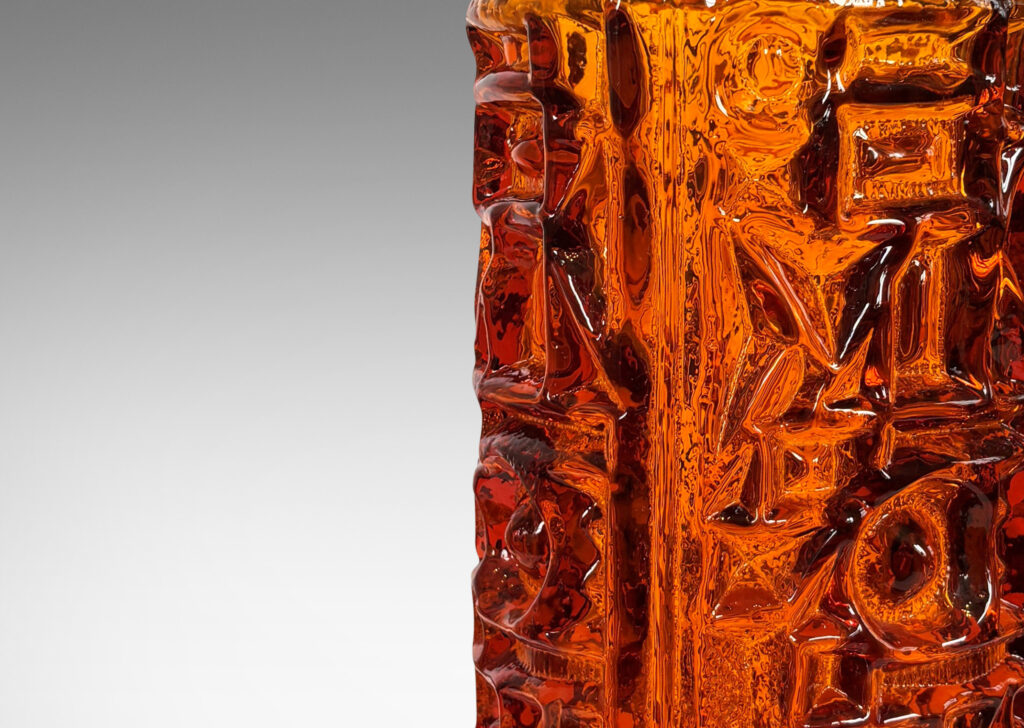 Gallery BAC round canister forms surrounded in geometric reliefs in a warm saturated whisky tone