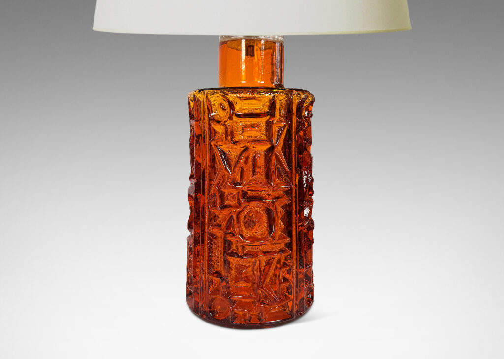 Gallery BAC round canister forms surrounded in geometric reliefs in a warm saturated whisky tone