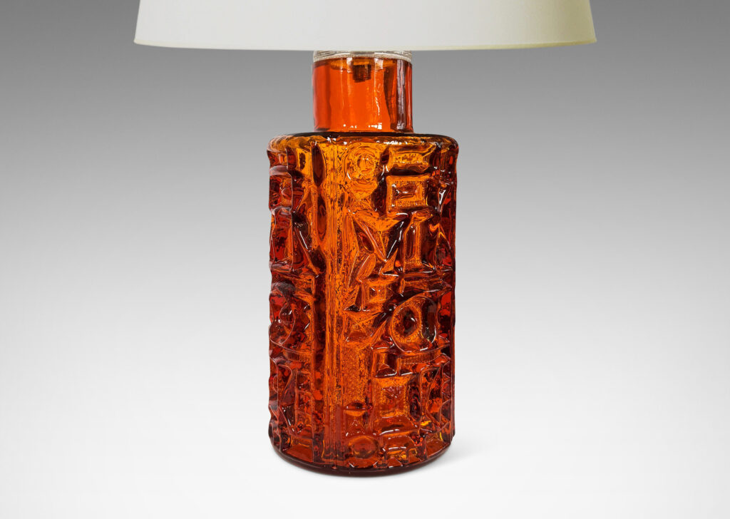 Gallery BAC round canister forms surrounded in geometric reliefs in a warm saturated whisky tone