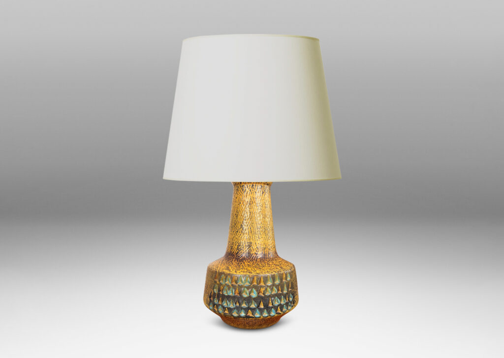 Gallery BAC floating drum form with wide conical neck, covered in a carved texture and ornamented with triangle motifs, and glazed in a mustard gold tone, with dark gray and turquoise elements