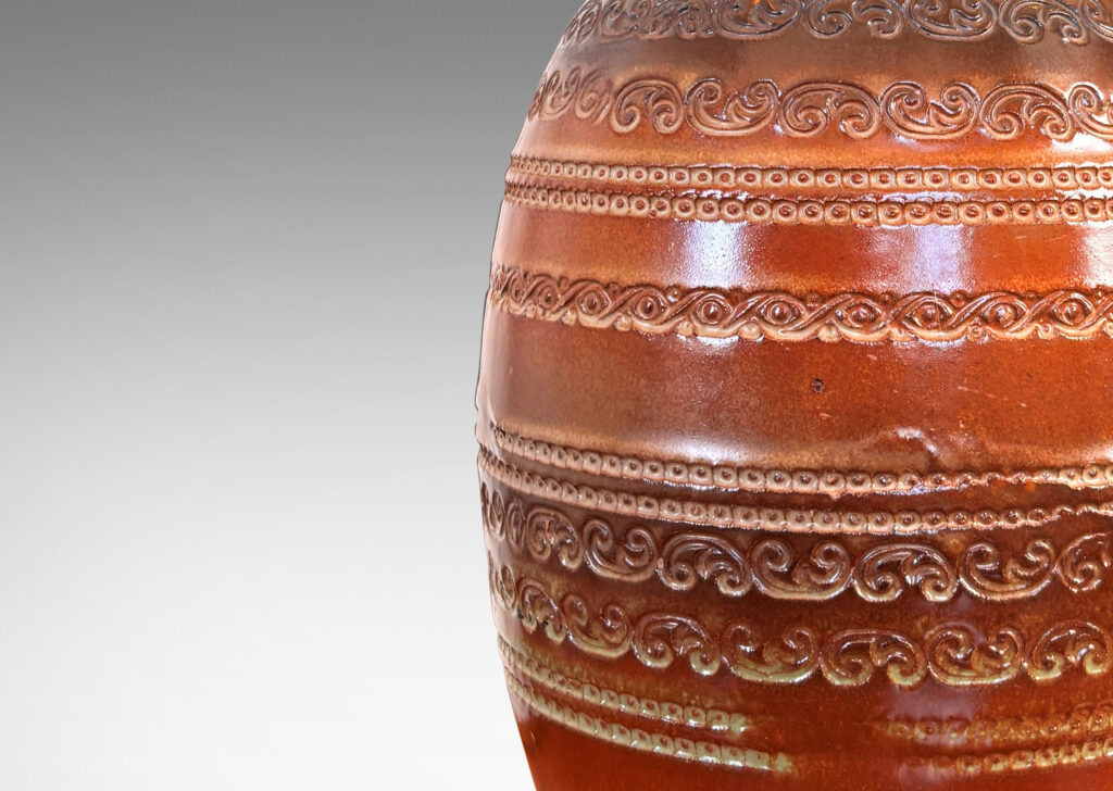 Gallery BAC ovoid form with neck, impressed with bands of ornaments evoking tooled leather, glazed in semi-shine brown, with darker brown and green accents