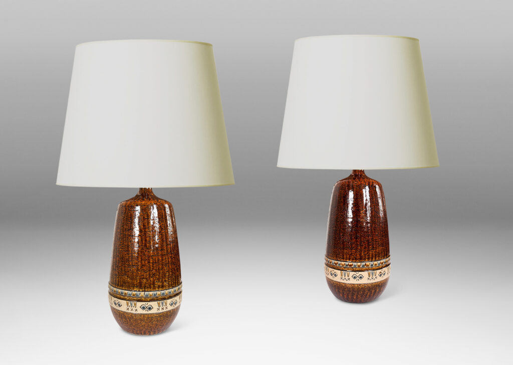 Gallery BAC having grog-textured ovoid cylindrical forms in shiny warm brown with bands of carved geometric designs in ivory, gold and blue