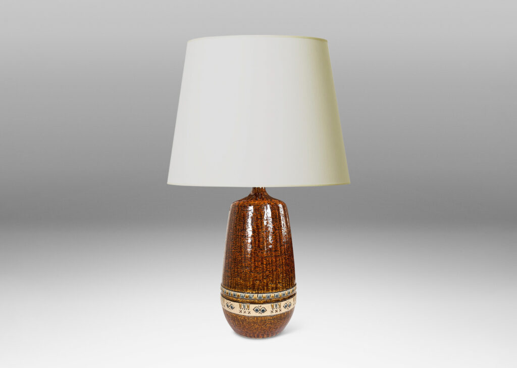 Gallery BAC having grog-textured ovoid cylindrical forms in shiny warm brown with bands of carved geometric designs in ivory, gold and blue