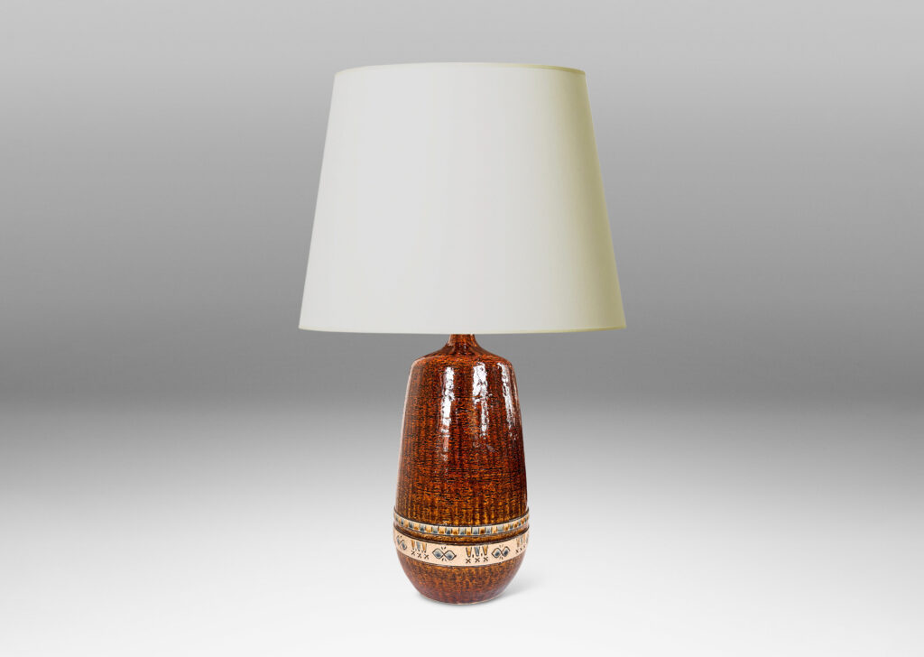 Gallery BAC having grog-textured ovoid cylindrical forms in shiny warm brown with bands of carved geometric designs in ivory, gold and blue