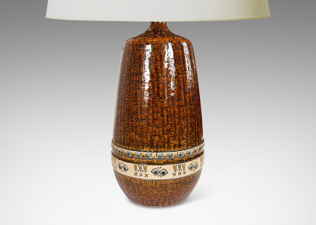 Gallery BAC having grog-textured ovoid cylindrical forms in shiny warm brown with bands of carved geometric designs in ivory, gold and blue