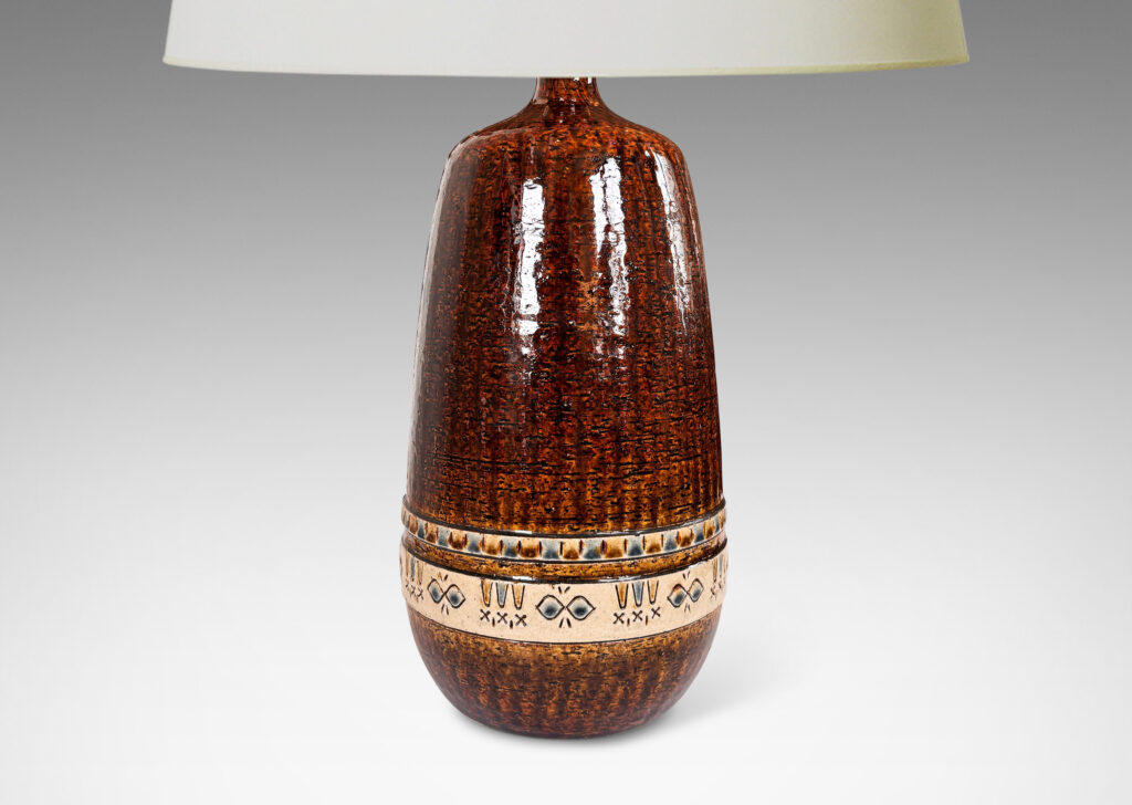 Gallery BAC having grog-textured ovoid cylindrical forms in shiny warm brown with bands of carved geometric designs in ivory, gold and blue