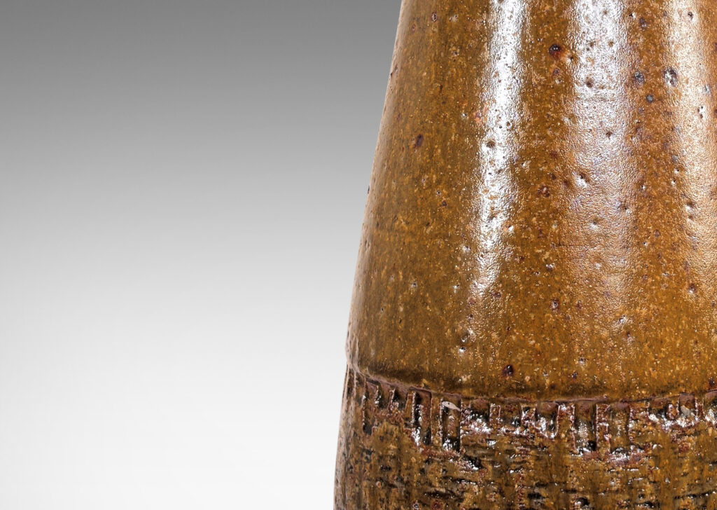 Gallery BAC conical form with rounded edge over a reveal foot, and textured base, glazed in a greenish mustard brown