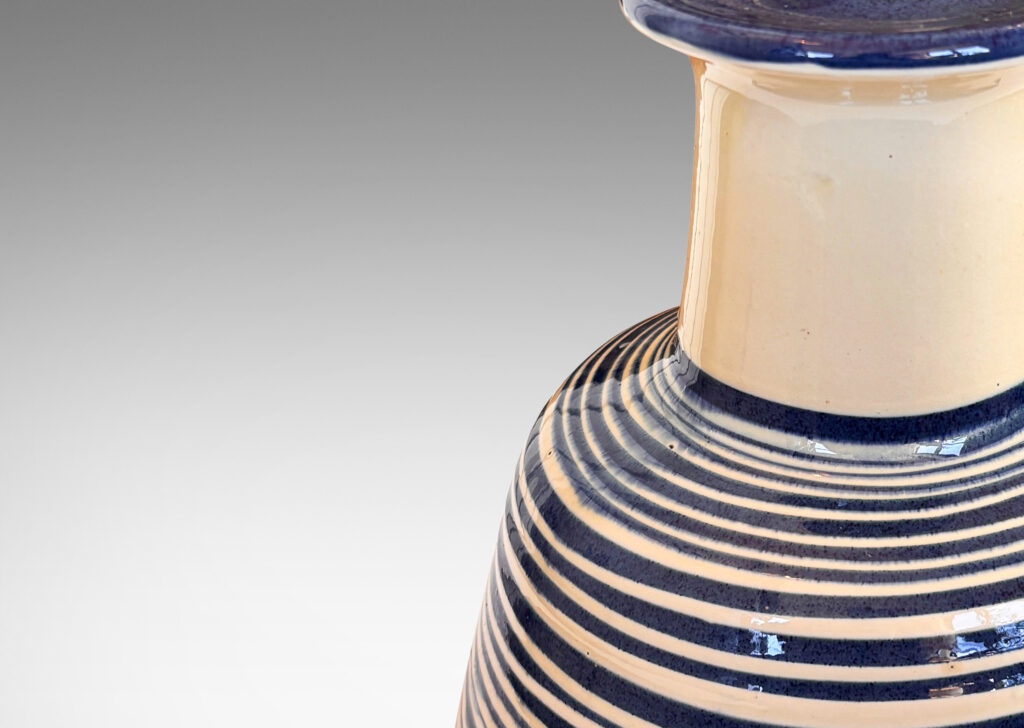 Gallery BAC angled drum form, wide neck and flange top, glazed in ivory with spiraling pinstripes in dark blue