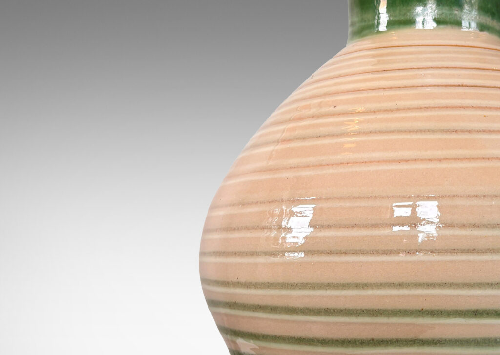 Gallery BAC globe form with wide neck and carved spiraling ridges, glazed in shiny ivory, with green neck and partial pinstripes