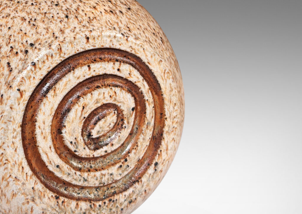 Gallery BAC squared globe form with carved concentric circle ornaments, glazed in stippled black and taupe over pale beige, with brown accents to motifs