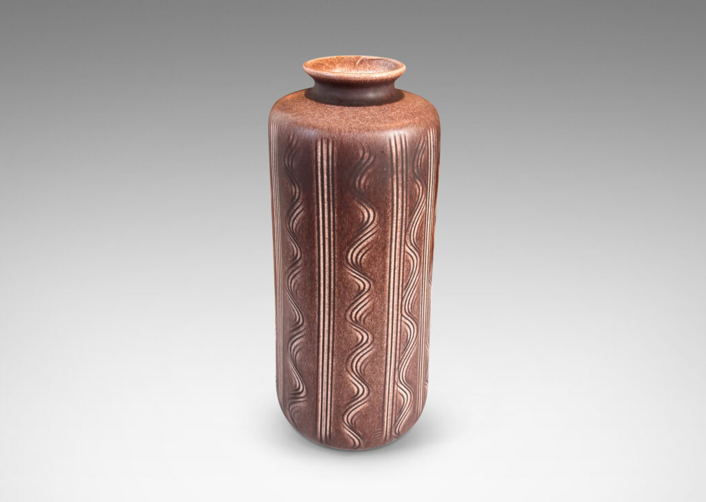Gallery BAC cylindrical form with carved vertical stripes and waves, and outward curved lip, glazed in an eggshell finish mocha brown