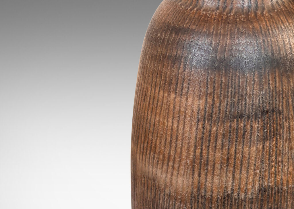 Gallery BAC organically modeled ovoid form with flanged base, textured with carved vertical pinstripes, and glazed in matte brown