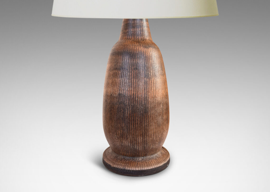 Gallery BAC organically modeled ovoid form with flanged base, textured with carved vertical pinstripes, and glazed in matte brown