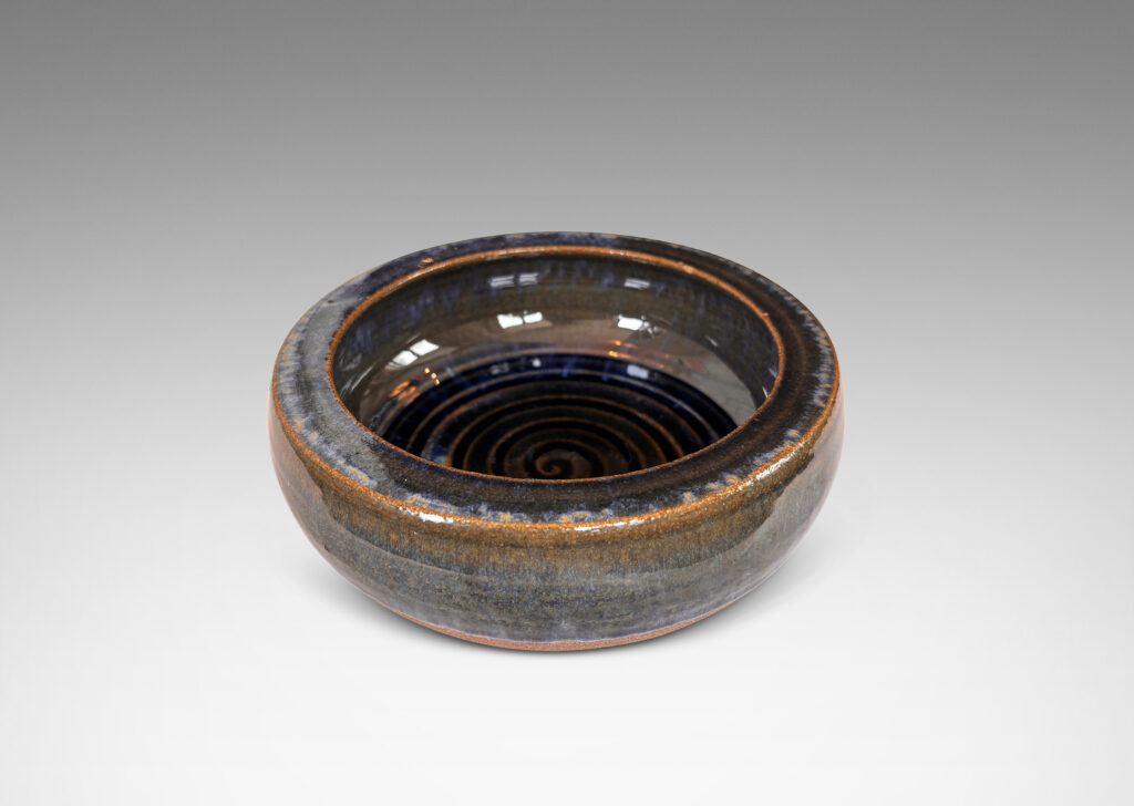 Gallery BAC round form with inward curving sides and carved spiral inside, partially glazed in glossy blue and green