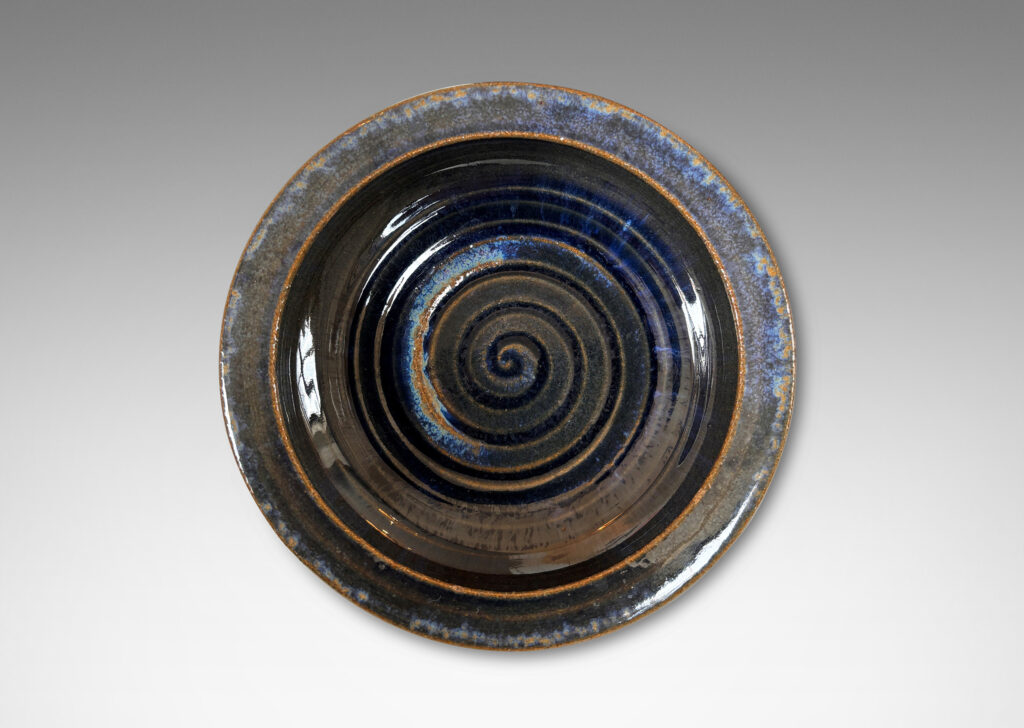 Gallery BAC round form with inward curving sides and carved spiral inside, partially glazed in glossy blue and green