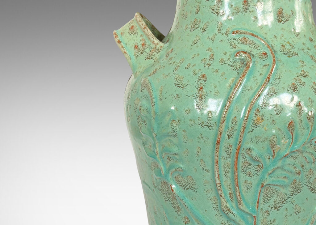 Gallery BAC gourd form with wide mouth, handles, and stylized floral reliefs, glazed in a mottled bright ceadon