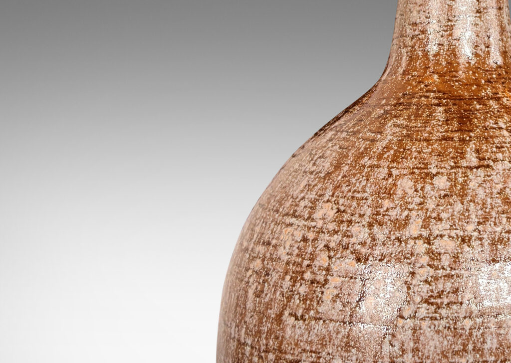 Gallery BAC bulbous form with tall, conical neck, glazed in pale beige over raw umber brown