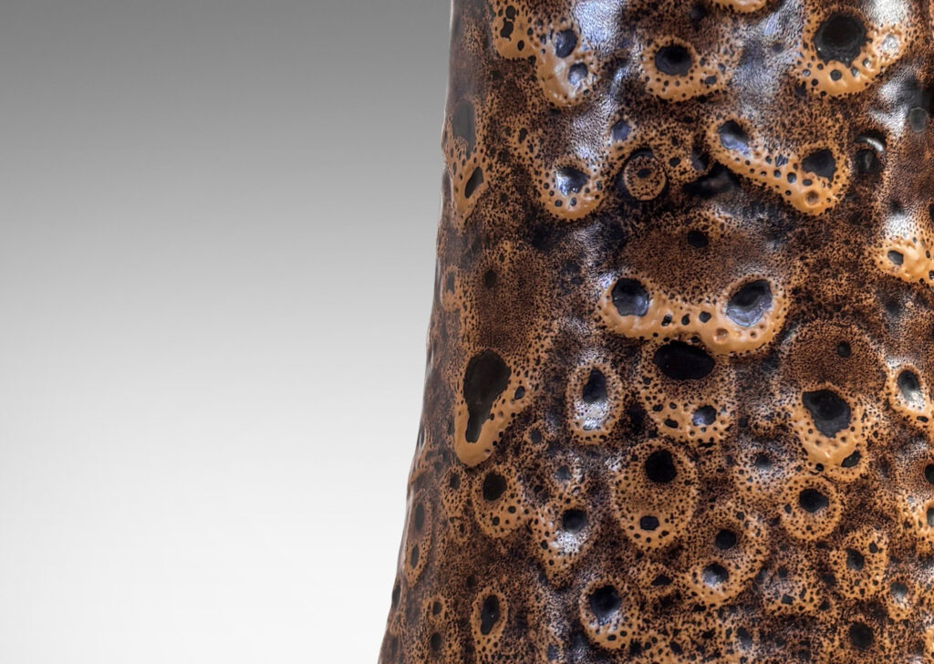 Gallery BAC bell form with ridged neck, glazed in a dark brown with frothy tan “lava” texture