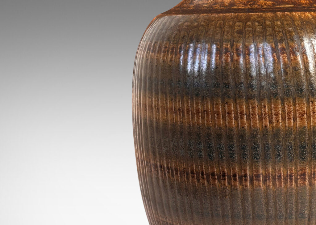 Gallery BAC tapered ovoid form with ribbed texture and spouting neck and mouth, glazed in a flowing dark brown