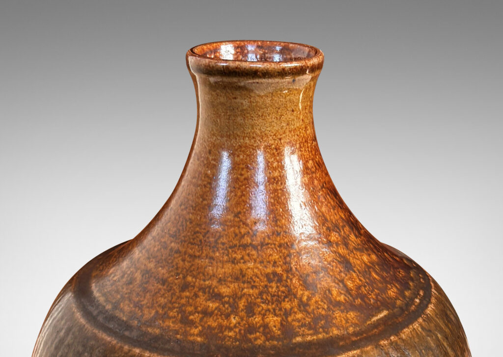 Gallery BAC tapered ovoid form with ribbed texture and spouting neck and mouth, glazed in a flowing dark brown