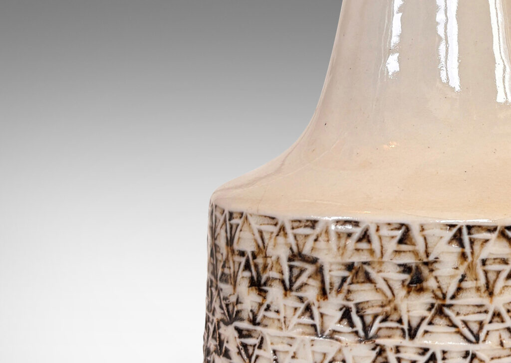 Gallery BAC low drum form with carved relief of triangular motifs and a tall sprouting neck