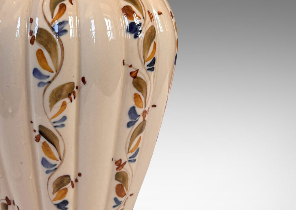 Gallery BAC vertically lobed tapered form, glazed in ivory with hand-painted foliage ornaments in drab green, brown and blue