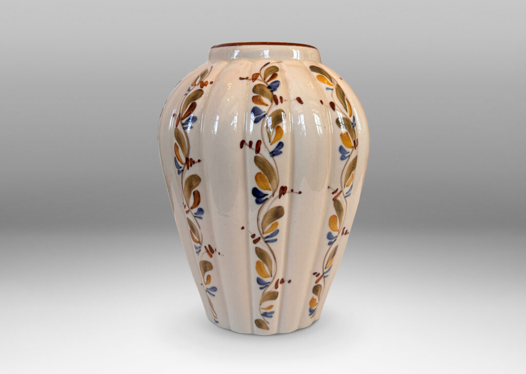 Gallery BAC vertically lobed tapered form, glazed in ivory with hand-painted foliage ornaments in drab green, brown and blue