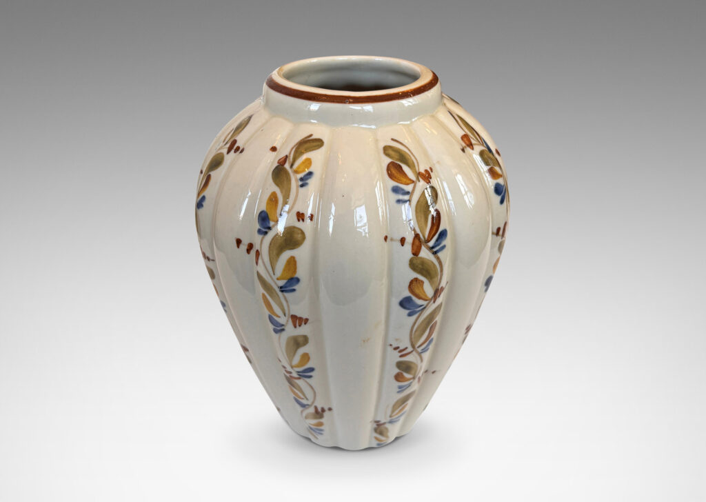 Gallery BAC vertically lobed tapered form, glazed in ivory with hand-painted foliage ornaments in drab green, brown and blue