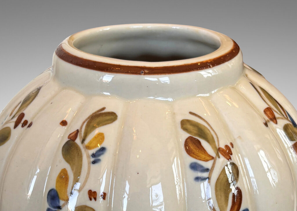 Gallery BAC vertically lobed tapered form, glazed in ivory with hand-painted foliage ornaments in drab green, brown and blue