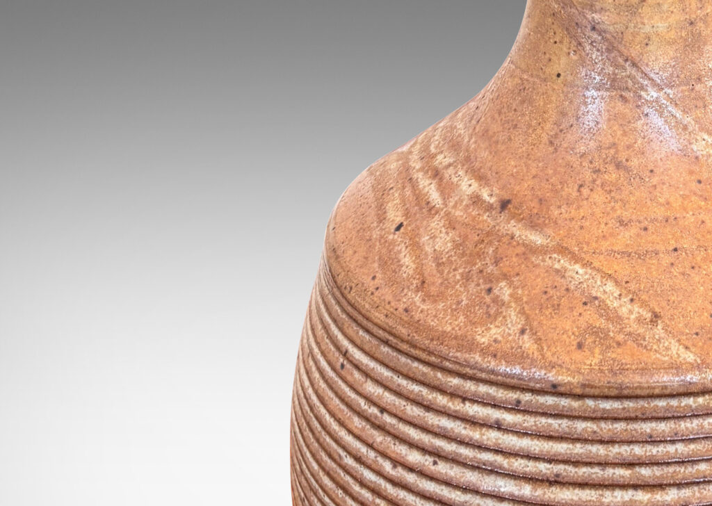 Gallery BAC jug-like form with ridged bulging body and smooth sprouting neck, glazed in light brown-pale taupe