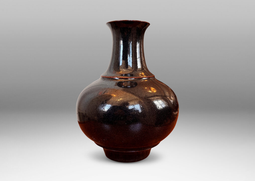 Gallery BAC compressed globe form with wide cove neck, glazed in shiny black with hints of oxblood red