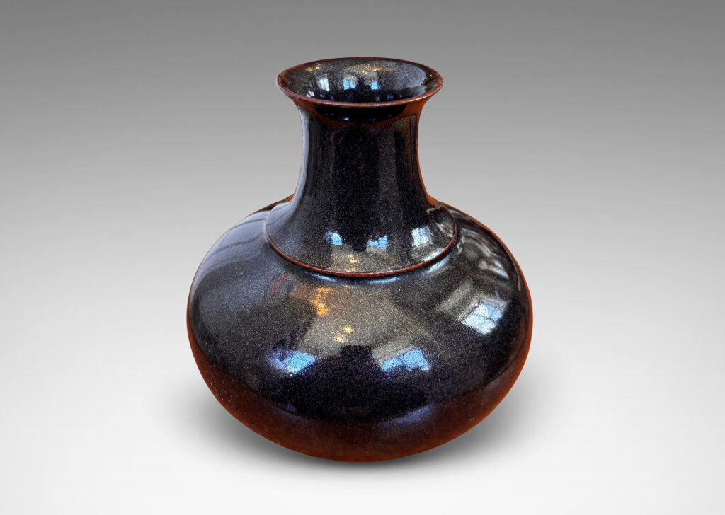 Gallery BAC compressed globe form with wide cove neck, glazed in shiny black with hints of oxblood red