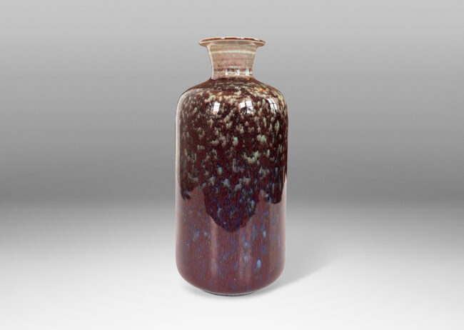 Gallery BAC cylindrical form with sprouting outstretched mouth, glazed in a shiny oxblood with hints of celadon