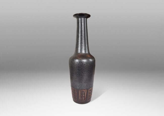 Gallery BAC large rationalized bottle form, with angled sides, impressed geometric motifs, tall neck, and flanged lip, in a charcoal gray luster and brown glaze