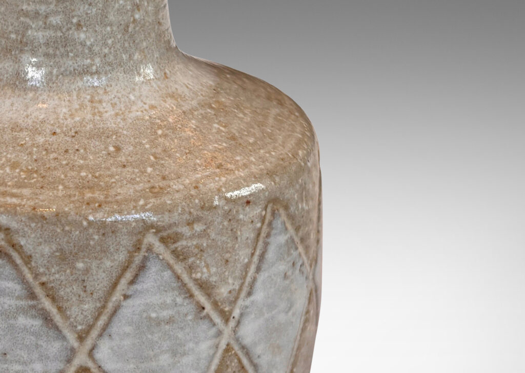 Gallery BAC drum form with carved harlequin design, and tall conical neck, glazed in warm pale gray with some diamond motifs in white