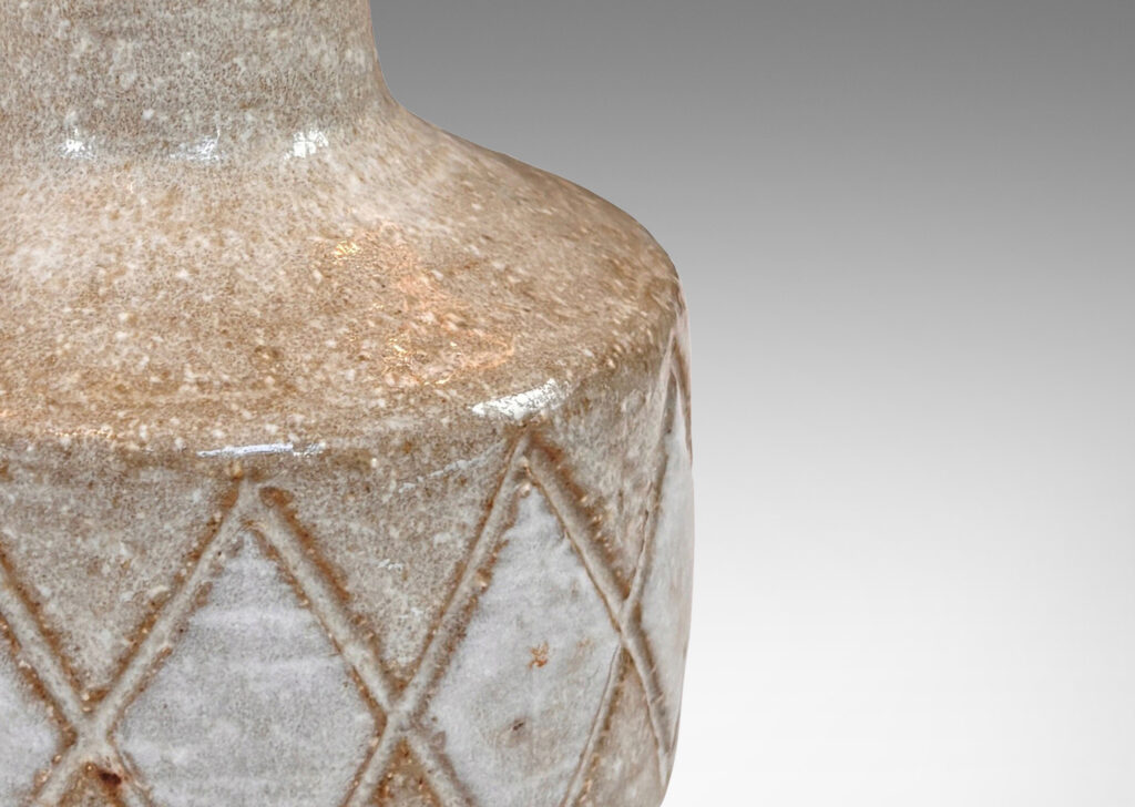 Gallery BAC drum form with carved harlequin design, and tall conical neck, glazed in warm pale gray with some diamond motifs in white