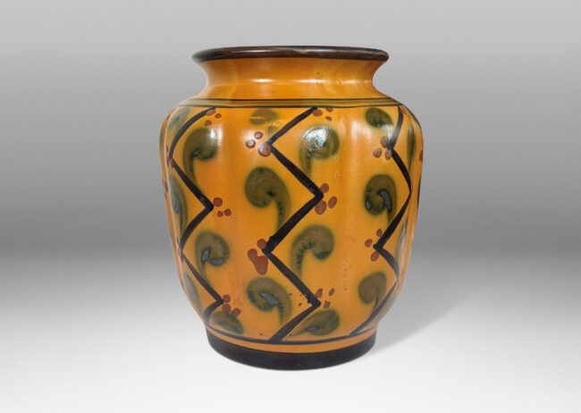 Gallery BAC lobed form with wide outstretched mouth, glazed in a toffee brown, with geometric pattern in black, brown and olive green