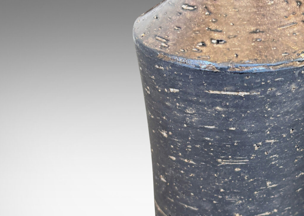 Gallery BAC concave sided cylindrical forms with grog texture and matte brown glaze, with shiny brown caps