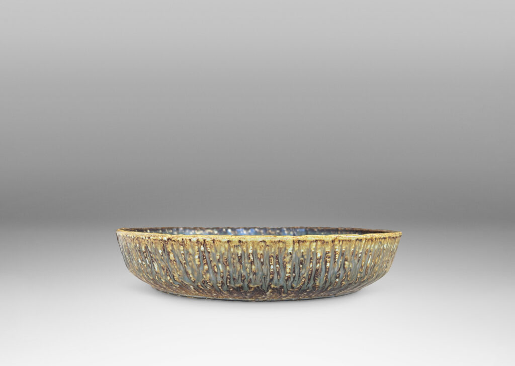 Gallery BAC clean form with angled sides, with carved surface texture and flowing brown glaze