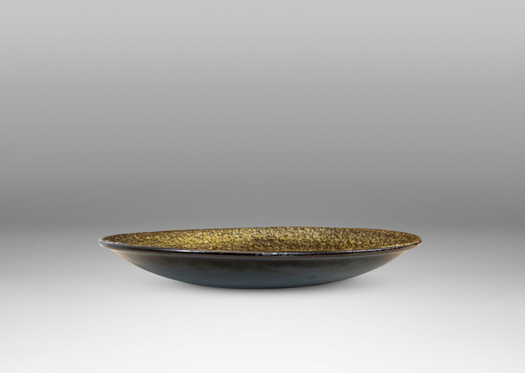 Gallery BAC shallow round form with a rustically textured and concentrically grooved interior glazed in black and green-gray, and a smooth exterior in gloss black