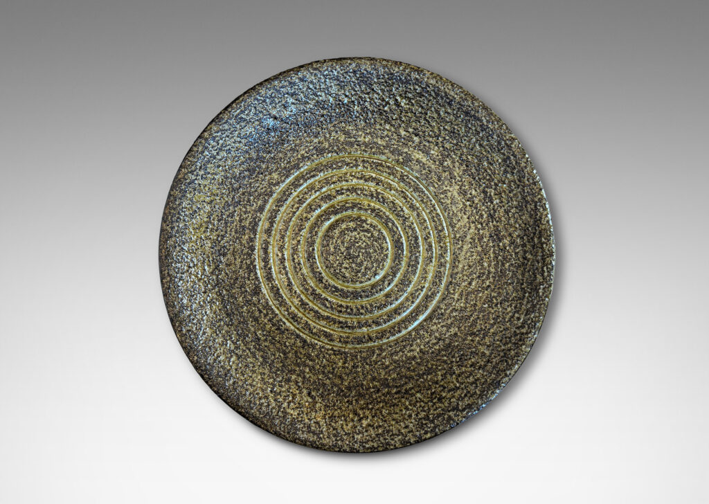 Gallery BAC shallow round form with a rustically textured and concentrically grooved interior glazed in black and green-gray, and a smooth exterior in gloss black