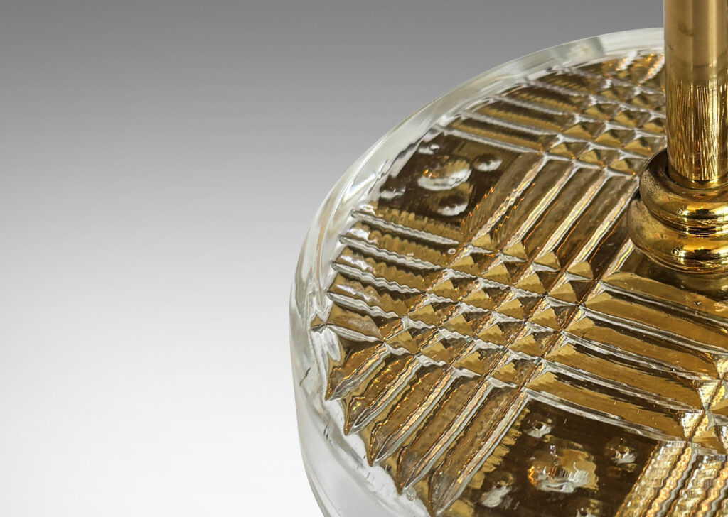 Gallery BAC disk bases in glass with reverse-cut crosshatch pattern, backed by a brass for a shimmering gold effect, with slender brass stands
