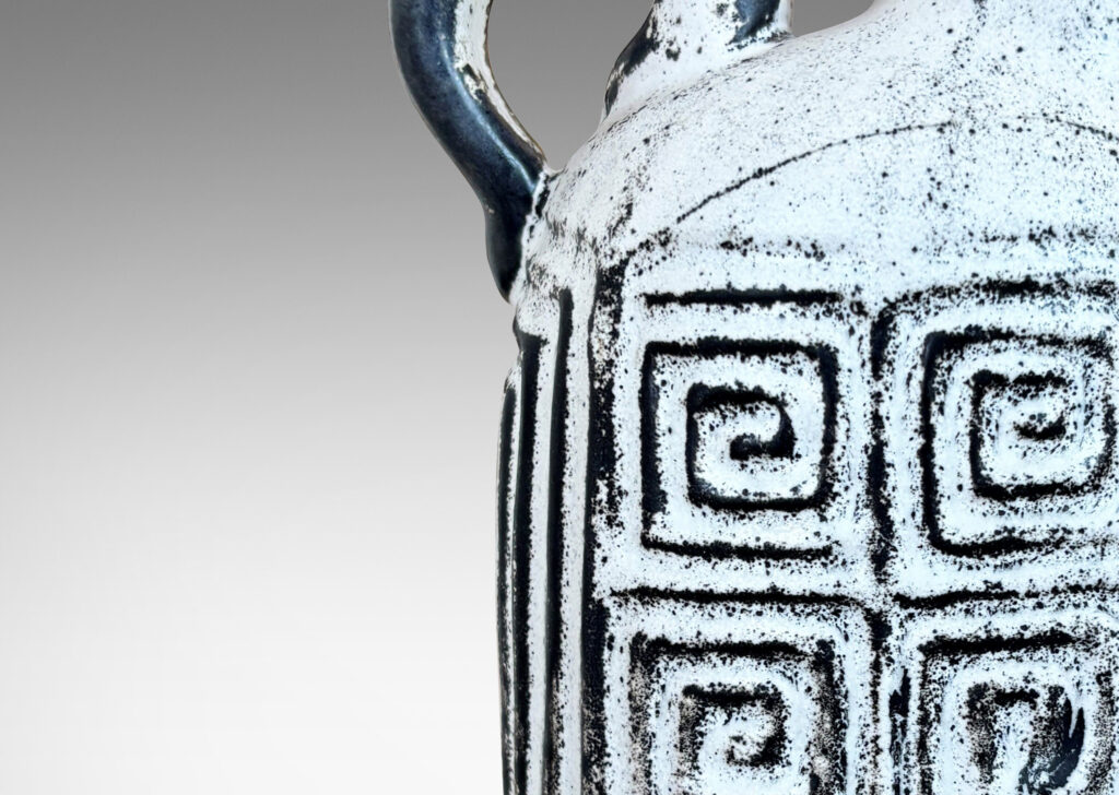 Gallery BAC compressed ovoid form, with spout mouth, loop handle, and Greek key relief design, glazed in white-black