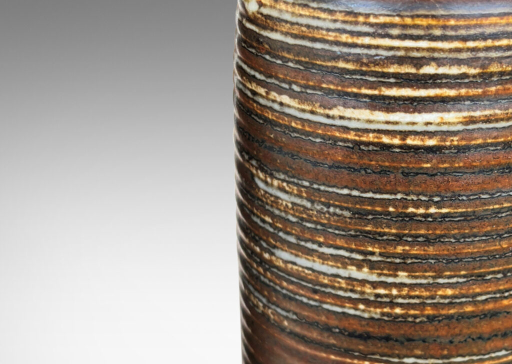 Gallery BAC ridged cylindrical forms glazed in a warm brown and pale gray “Sung” glaze, with matte brown angled plinths