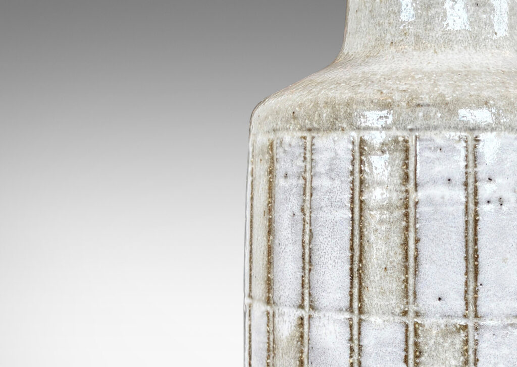Gallery BAC cylindrical form with carved grid design, and tall conical neck, glazed in pale gray and white
