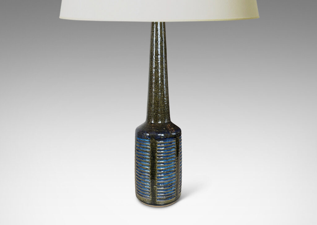 Gallery BAC drum form with vertical bands of carved lines, and tall conical neck, in a grog texture; glazed in gloss dark green with blue